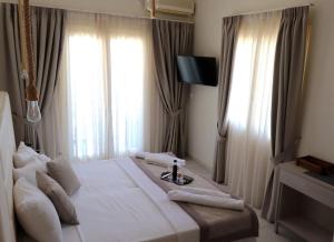 a bedroom with a large white bed with windows at marilena in Nea Epidavros