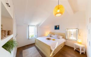a white bedroom with a bed and a potted plant at Golden Summerhouse in Komiža