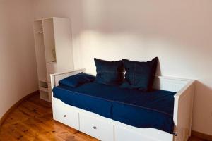 un letto bianco con cuscini blu in una camera da letto di Casa do Rio. Sossego à beira rio. a Rio de Onor