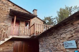 a stone building with a wooden balcony on top of it at Casa do Rio. Sossego à beira rio. in Rio de Onor