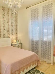 um quarto com uma cama rosa e uma janela em LA CONCHIGLIA em Marsala
