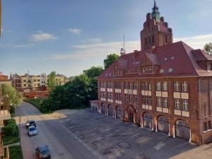 a large brick building with a clock tower on a street at Koszalin-Old Town Apartment in Koszalin