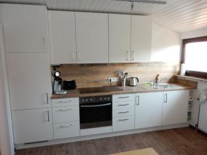 uma cozinha branca com armários brancos e um lavatório em Business-Apartment Braun em Abstatt