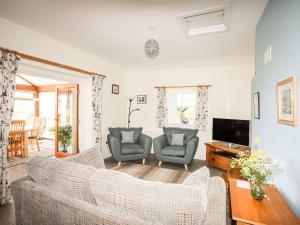uma sala de estar com duas cadeiras e uma televisão em Tymynydd Cottage em Rhoscolyn