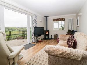 uma sala de estar com um sofá e uma televisão em Meadowlea Cottage em Plymouth