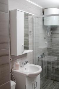 La salle de bains blanche est pourvue d'un lavabo et d'une douche. dans l'établissement Apartments Marta, à Žabljak