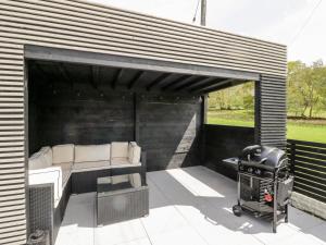 a covered patio with a couch and a grill at Maes Meillion in Dolgellau