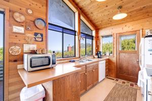 a kitchen with a microwave on a counter with windows at Arthur's Court in Oceanside +25 photos