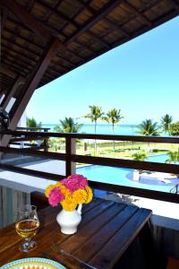 a table with a vase of flowers on a balcony at Flat Maui Beach- Com vista e de frente para o mar in Tamandaré
