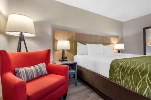 une chambre d'hôtel avec un lit et un fauteuil rouge dans l'établissement Comfort Inn & Suites, à Liverpool