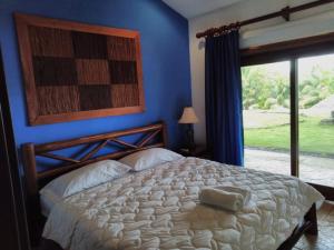 1 dormitorio con 1 cama grande y pared azul en Casa Caletas Boutique Hotel en Puerto Coyote