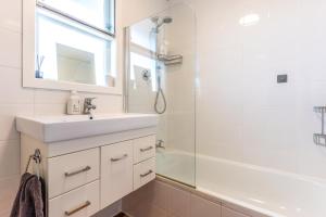 une salle de bain blanche avec un lavabo et un miroir dans l'établissement Ti Cottage - Stay Waiheke, à Oneroa 21 autres photos