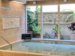 Hotel Palm Royal Naha Kokusai Street في ناها: حوض استحمام ساخن في غرفة بها نباتات