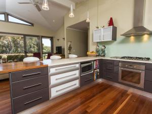 cocina con electrodomésticos de acero inoxidable y suelo de madera en Tura Beachhouse in Dolphin Cove, en Tura Beach