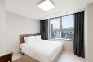 东海市Donghae Oceancity Residence Hotel的一间带床和大窗户的卧室