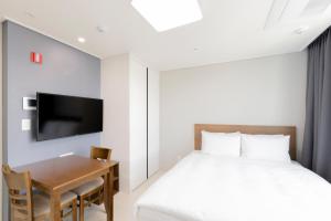 1 dormitorio con 1 cama, escritorio y TV en Donghae Oceancity Residence Hotel, en Donghae