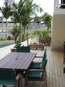 a wooden table and chairs on a patio with palm trees at Paihia Apartments in Paihia