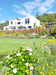 a house behind a fence with a garden with flowers at Te Aputa Lodge formerly La Casa Te Puru Lodge in Te Puru