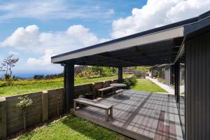 une terrasse couverte avec un banc et une table de pique-nique dans l'établissement Whakamaria - Leigh Holiday Home, à Leigh