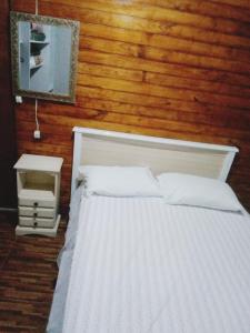 Un dormitorio con una cama blanca con una pared de madera. en villa foresti macedo gramado, en Gramado