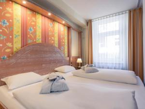 a bedroom with two beds and a large window at Mercure Hotel Berlin Mitte in Berlin