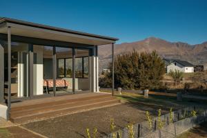 a house with a deck with mountains in the background at Bull Ridge Escape - Wanaka Holiday Home in Wanaka