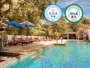 uma piscina com cadeiras e guarda-sóis ao lado de um hotel em Sailom Hotel Hua Hin - SHA Extra Plus em Hua Hin