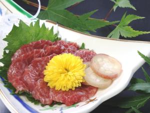 a plate of food with meat and a yellow flower at Hotel Omodaka in Yamanouchi