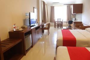 a hotel room with two beds and a desk with a television at HOTEL & WISMA BINTANG JADAYAT in Bogor