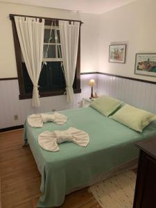 Un dormitorio con una cama verde con toallas. en Fachoalto Budget en Petrópolis