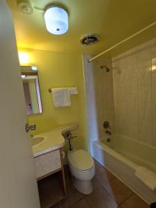 a bathroom with a toilet and a sink and a tub at Great Plains Budget Inn in Lincoln