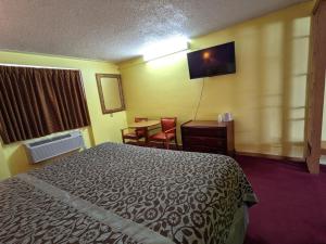 a hotel room with a bed and a table and a desk at Great Plains Budget Inn in Lincoln