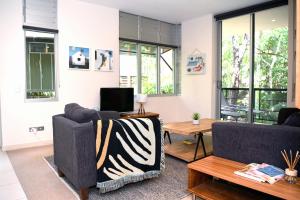 a living room with two couches and a tv at Private Retreat in the heart of Noosa in Noosa Heads