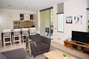 een woonkamer met een bank en een tv en een keuken bij Private Retreat in the heart of Noosa in Noosa Heads