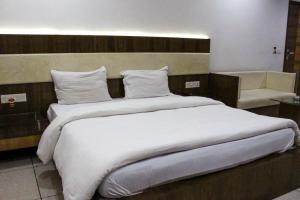 a large white bed in a hotel room at Hotel Apex Inn in Vapi