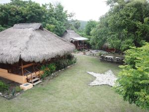 een huis met een rieten dak en een grasveld bij Atauro Dive Resort in Beloi