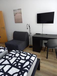 ein Wohnzimmer mit einem Sofa, einem Schreibtisch und einem TV in der Unterkunft Penzion Lokotka Děčín in Děčín