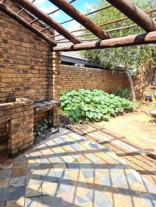 a patio with a brick wall and a wooden pergola at Baraka House in Midrand