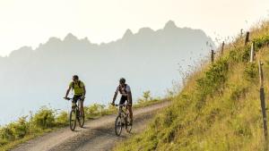 two people riding bikes down a dirt road at Hotel Alpin Tyrol - Kitzbüheler Alpen in Sankt Johann in Tirol +99 photos