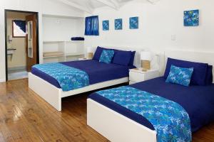 two beds in a bedroom with blue and white at Airlie Beach Magnums - Adults Only in Airlie Beach