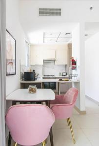 a kitchen with pink chairs and a table at Stella Stays Elegant Studio Dubai JVC Private Balcony in Dubai