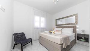 1 dormitorio con cama, silla y espejo en Hedonist-Luxury 2 bedroom apartment with private HOT TUB, garden and free parking, en Trogir