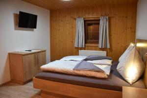 1 dormitorio con cama, ventana y TV en Bacherhof, en Söll