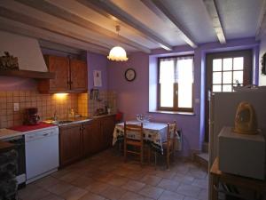 uma cozinha com paredes roxas e uma mesa e uma cozinha com uma mesa; em Gîte Le Val-d'Ajol, 5 pièces, 10 personnes - FR-1-589-139 em Le Val-dʼAjol