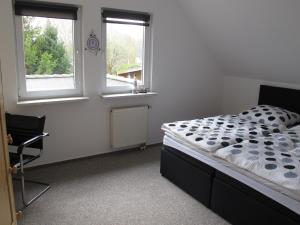 ein Schlafzimmer mit einem Bett, einem Stuhl und zwei Fenstern in der Unterkunft Ferienwohnung Ostseenähe in Hirschburg
