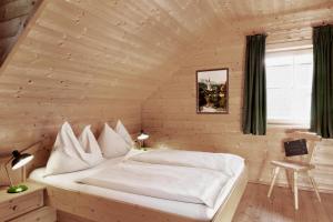 ein Schlafzimmer mit einem weißen Bett in einem Holzzimmer in der Unterkunft Das Dorf in der Stadt in Schladming