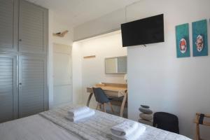 a bedroom with a bed and a desk with a television at KYMA Seafront Exceptional 2BD house in Naousa in Naousa