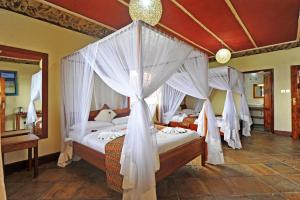 a bedroom with two beds with white drapes at Mwanzo Lodge in Naivasha