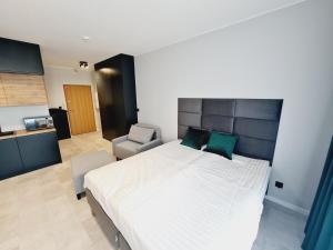 - une chambre avec un grand lit blanc et une chaise dans l'établissement Apartament Wałowa, à Gdańsk