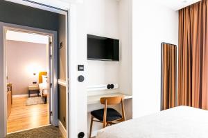 a bedroom with a bed and a chair and a television at LX SoHo Boutique Hotel by RIDAN Hotels in Lisbon